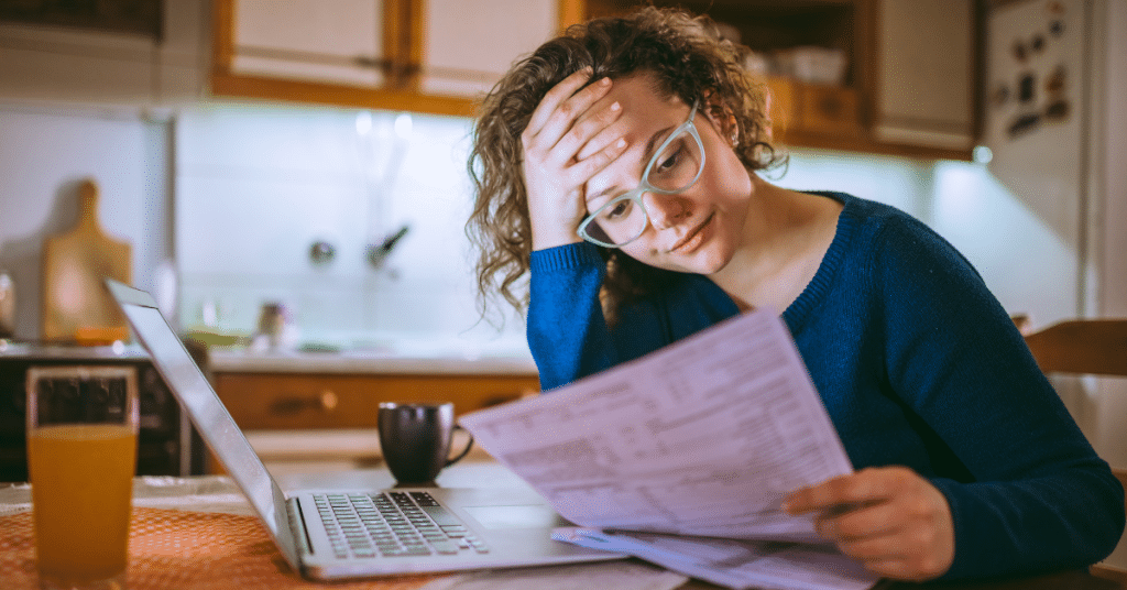 a worried woman who is looking a bills and paperwork which is contributing to young adult stress