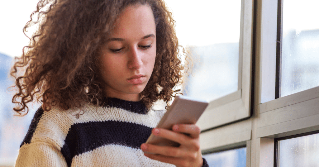 teen girl sadly looking at phone after experiencing negative messages on social media